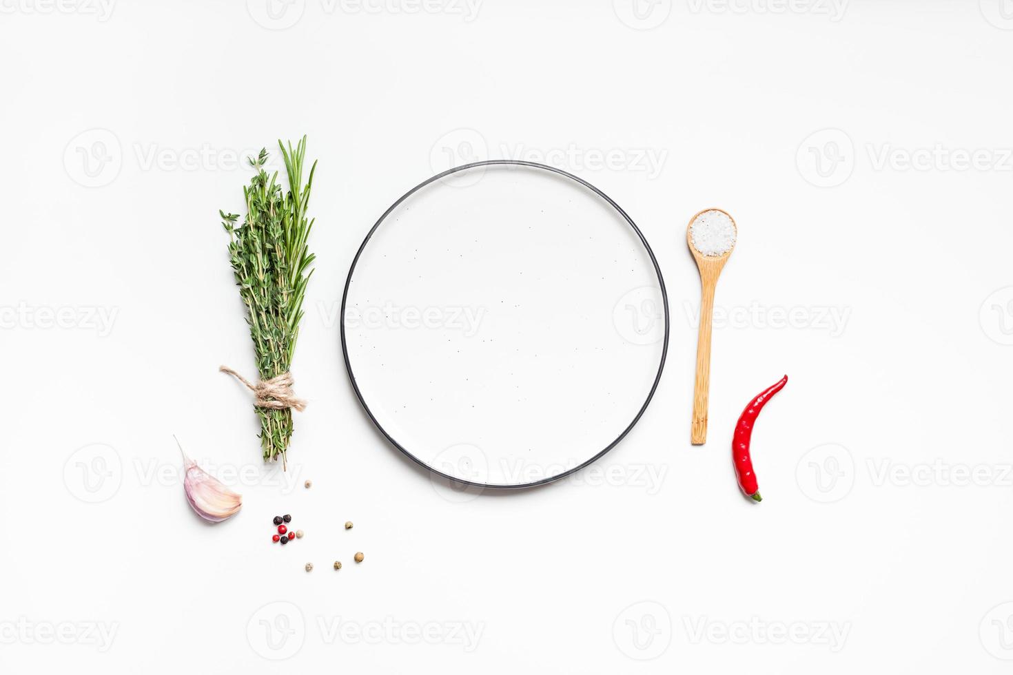 Empty plate with greens herbs and spices around photo