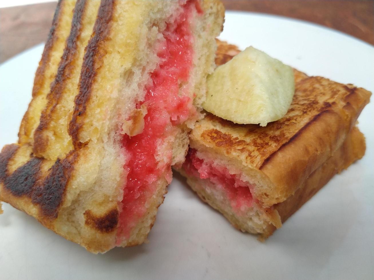 Morning breakfast a delicious toast with strawberry jam on a white plate. Good for used on business related to food, pastry, bakery, restaurant. photo