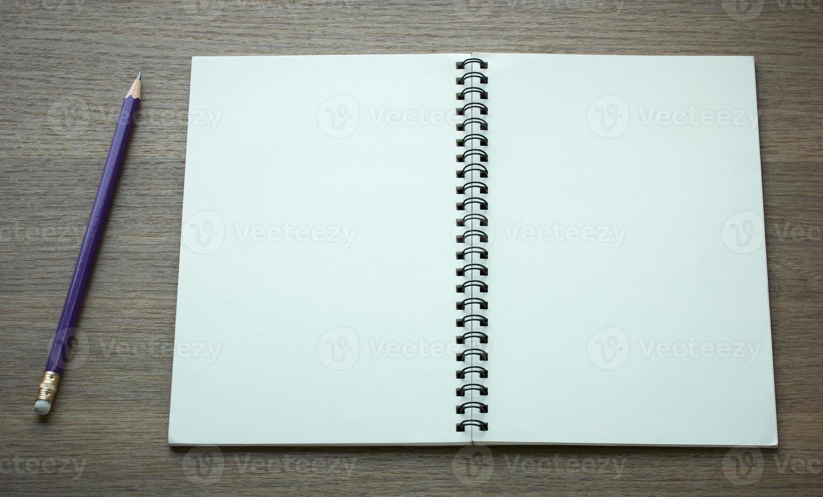 open spiral notebook and pencil on dark wood background photo