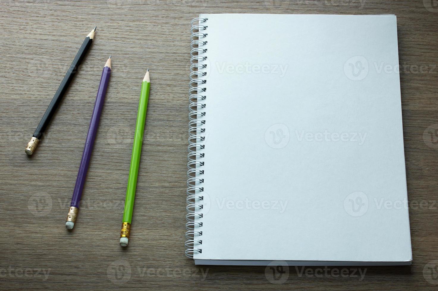 blank spiral notebook and pencil on dark wood background photo