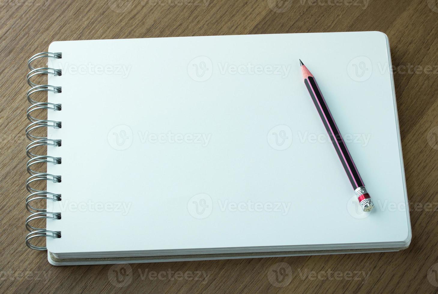 blank spiral notebook and pencil on dark wood background photo