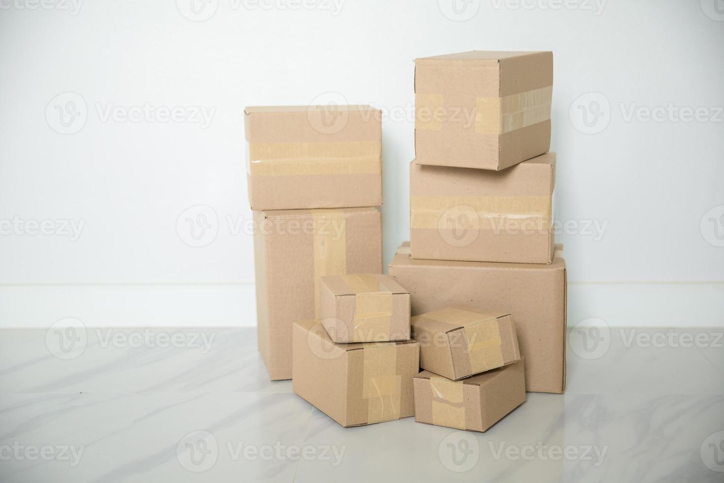 Stack of cardboard boxes for moving, Empty room with a white wall and cardboard boxes with unbranded barcode on the floor. Delivery of goods, shopping. Cardboard boxes on gray wall background. photo