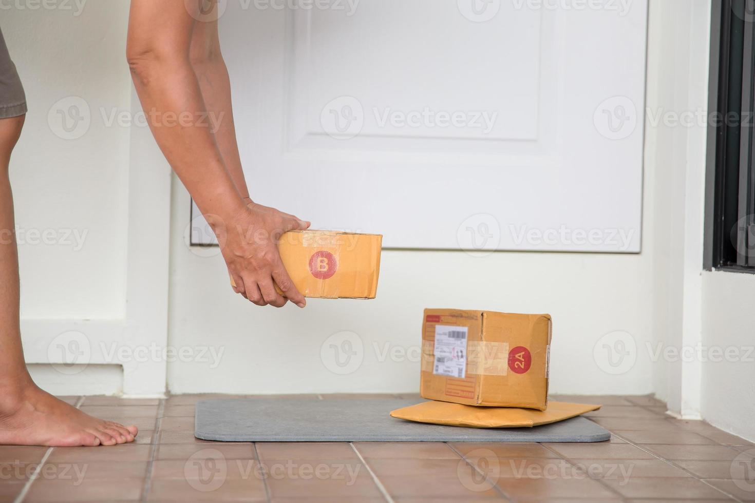 Woman collects parcel at door. box near door on floor. Online shopping, boxes delivered to your front door. Easy to steal when nobody is home. Parcel in cardboard box on doorstep. Delivery service photo