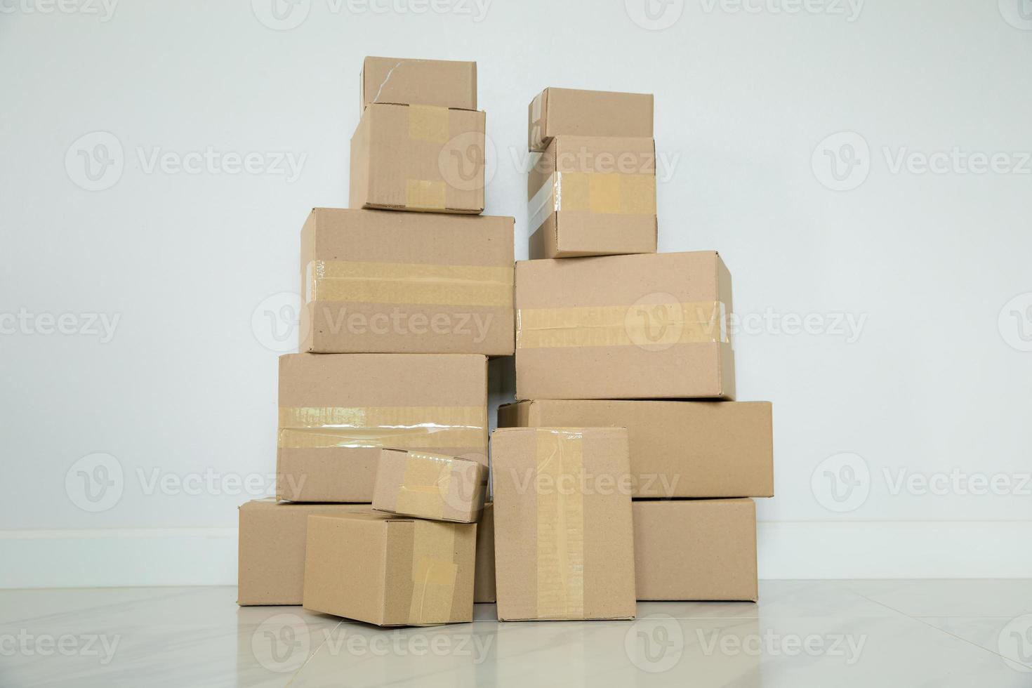 Stack of cardboard boxes for moving, Empty room with a white wall and cardboard boxes with unbranded barcode on the floor. Delivery of goods, shopping. Cardboard boxes on gray wall background. photo