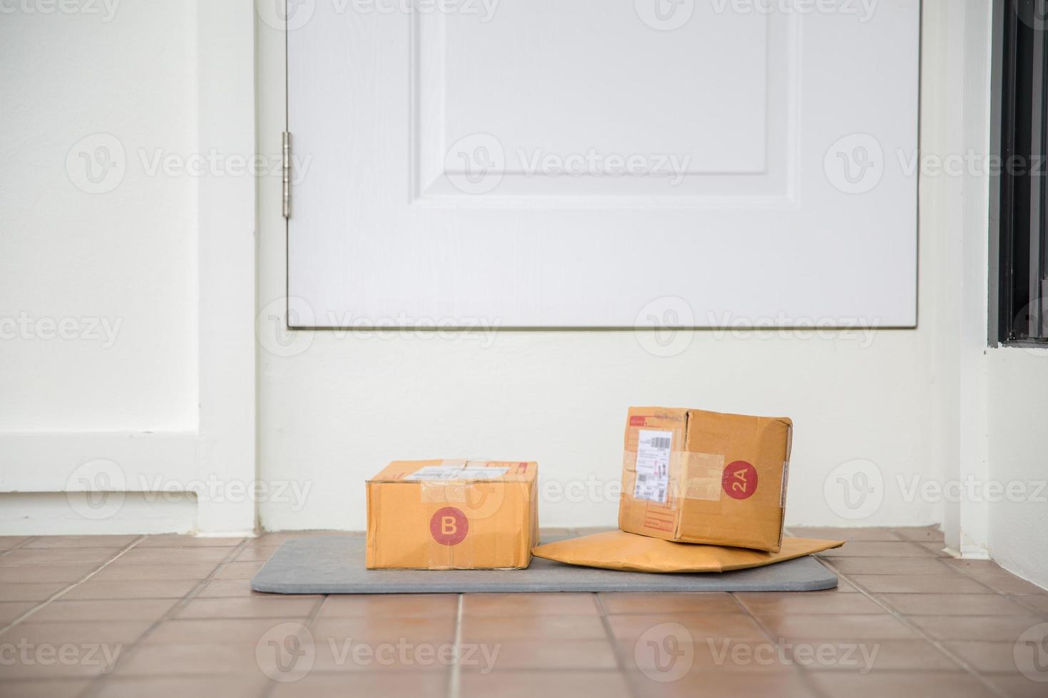 caja de paquetes de cartón cerca de la puerta en el piso. Compras en línea, cajas entregadas en la puerta de tu casa. fácil de robar cuando no hay nadie en casa. paquete en caja de cartón en la puerta. servicio de entrega foto