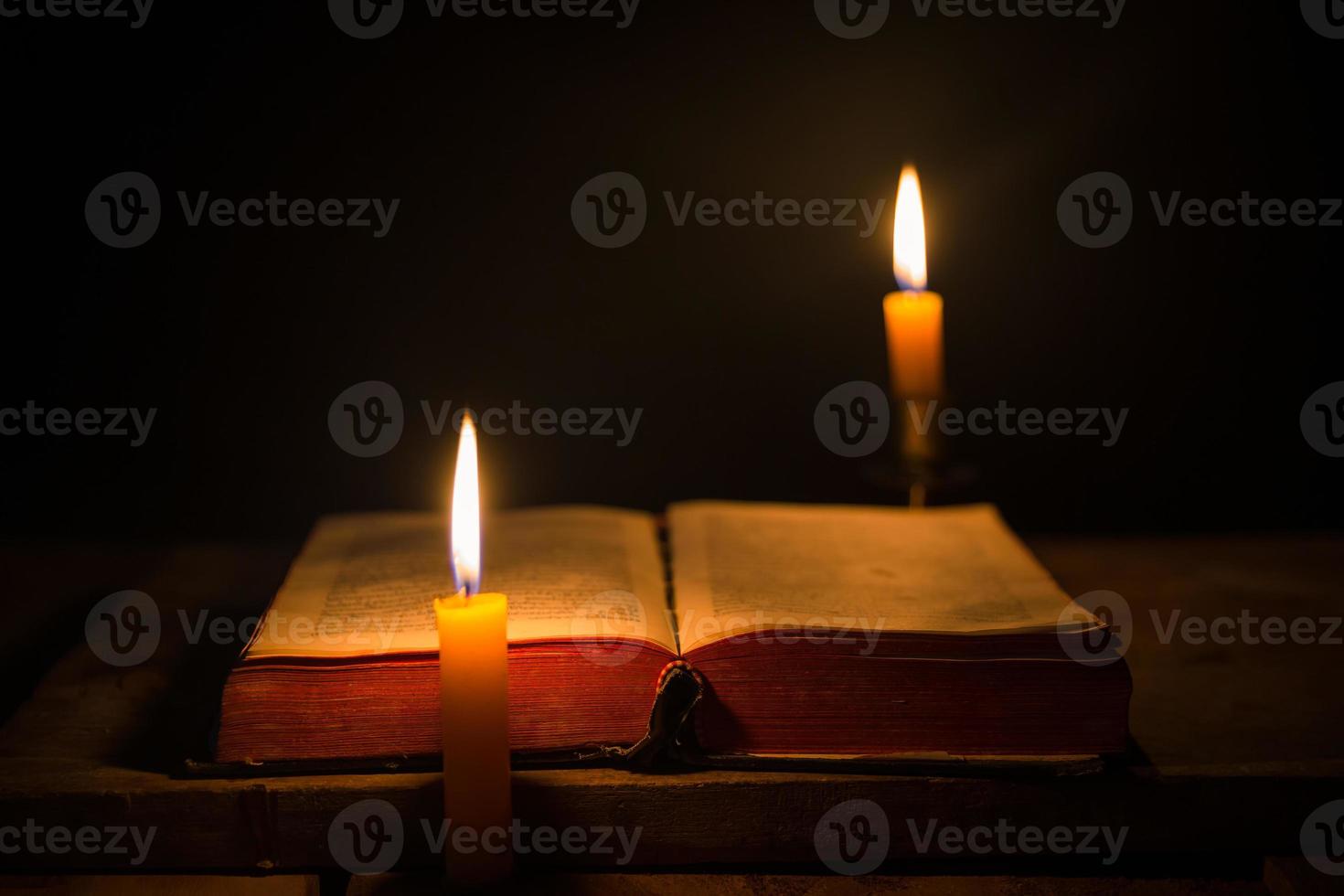Light candle with holy bible and cross or crucifix on old wooden background in church.Candlelight and open book on vintage wood table christianity study and reading in home.Concept of christ religion photo