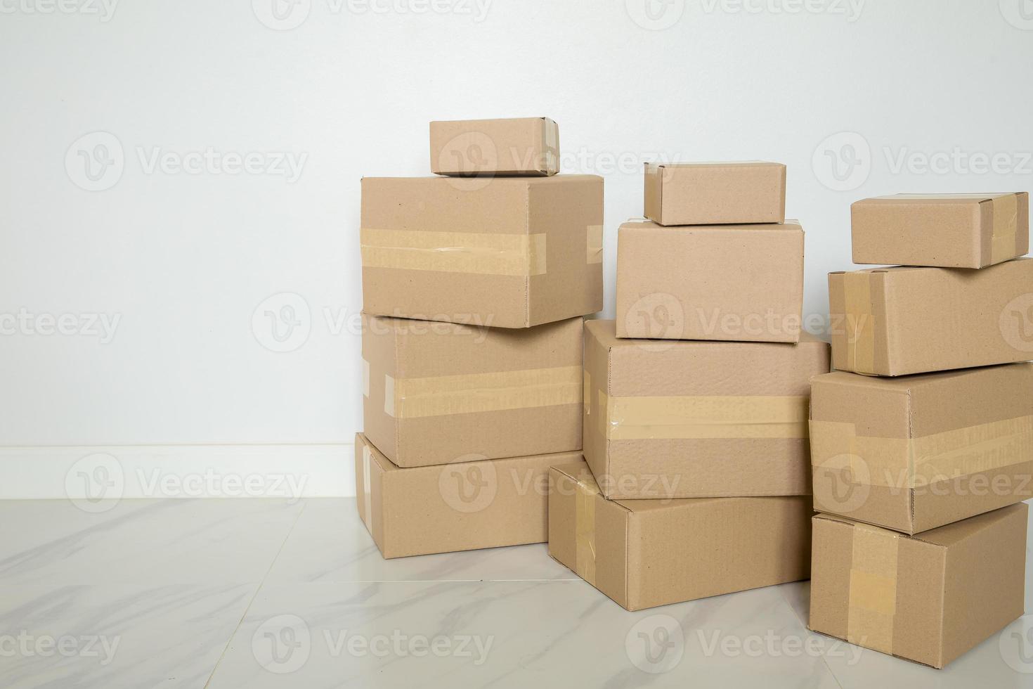 Stack of cardboard boxes for moving, Empty room with a white wall and cardboard boxes with unbranded barcode on the floor. Delivery of goods, shopping. Cardboard boxes on gray wall background. photo