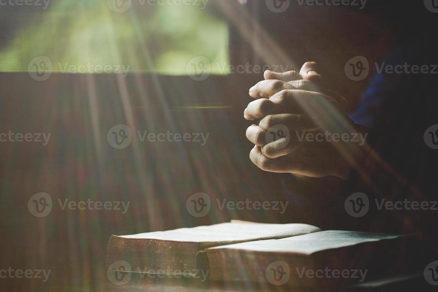 Hand folded in prayer to god on Holy Bible book in church concept for faith, spirituality and religion, woman person praying on holy bible in morning. christian catholic woman hand with Bible worship. photo