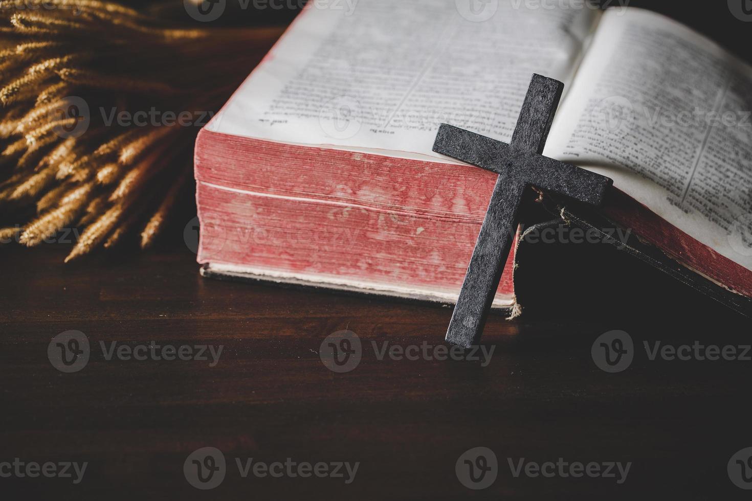 Holy bible book with cross or crucifix on old black wooden background. Christian catholic with protestant pray and study in church. Concept of cognition about faith god and religion, jesus spiritual. photo