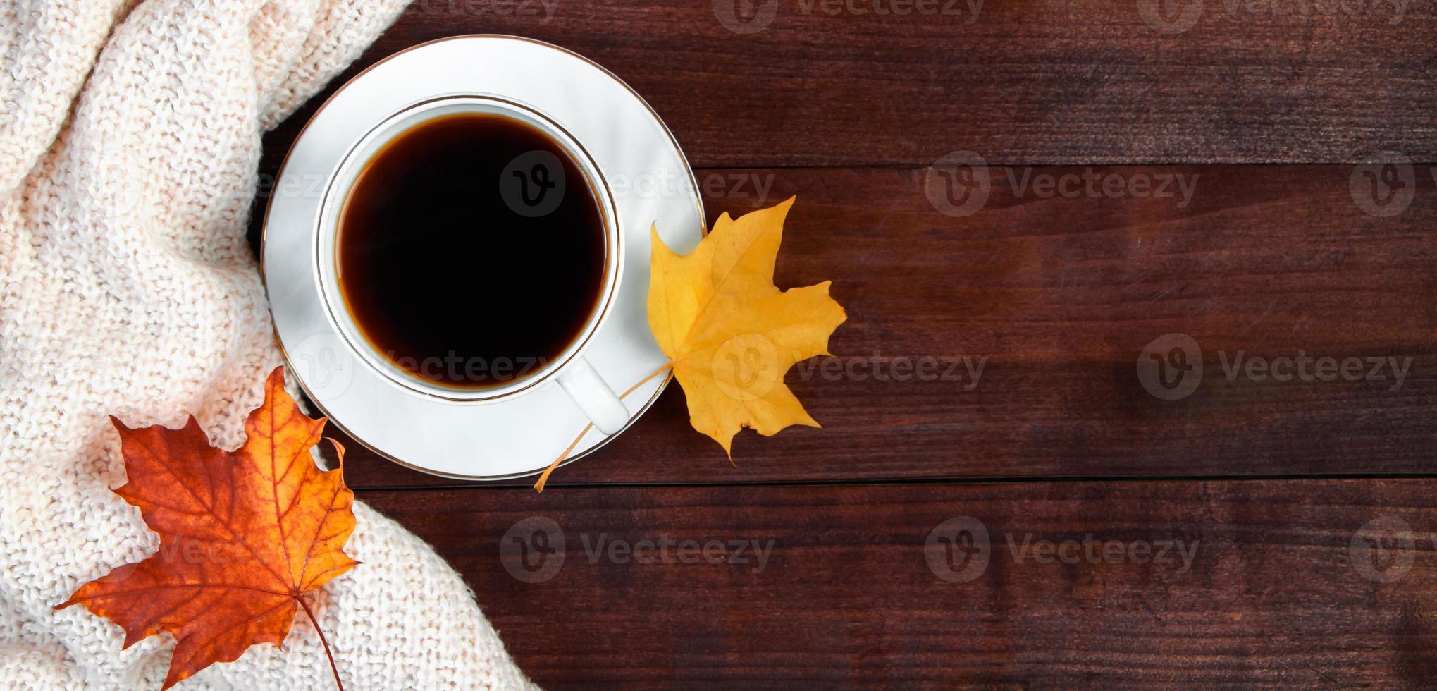 taza de café espresso caliente y hojas amarillas caídas sobre fondo de madera. concepto de mañana de otoño. foto