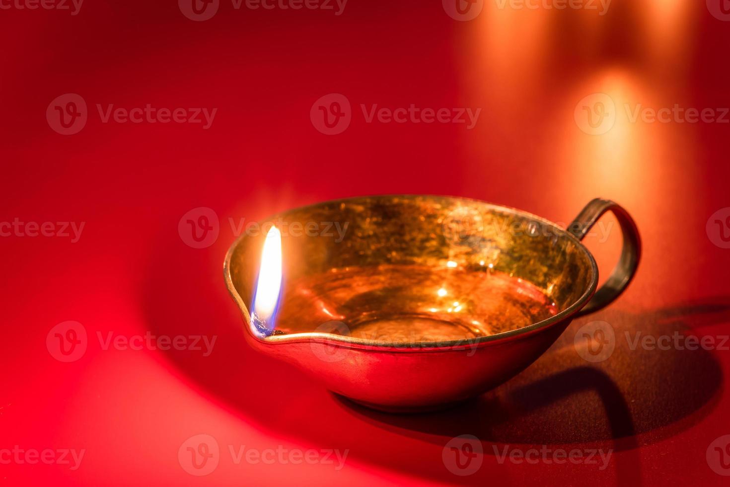 Burning diya oil lamp on red background. Celebrating the Indian traditional festival of light. Happy Diwali. photo