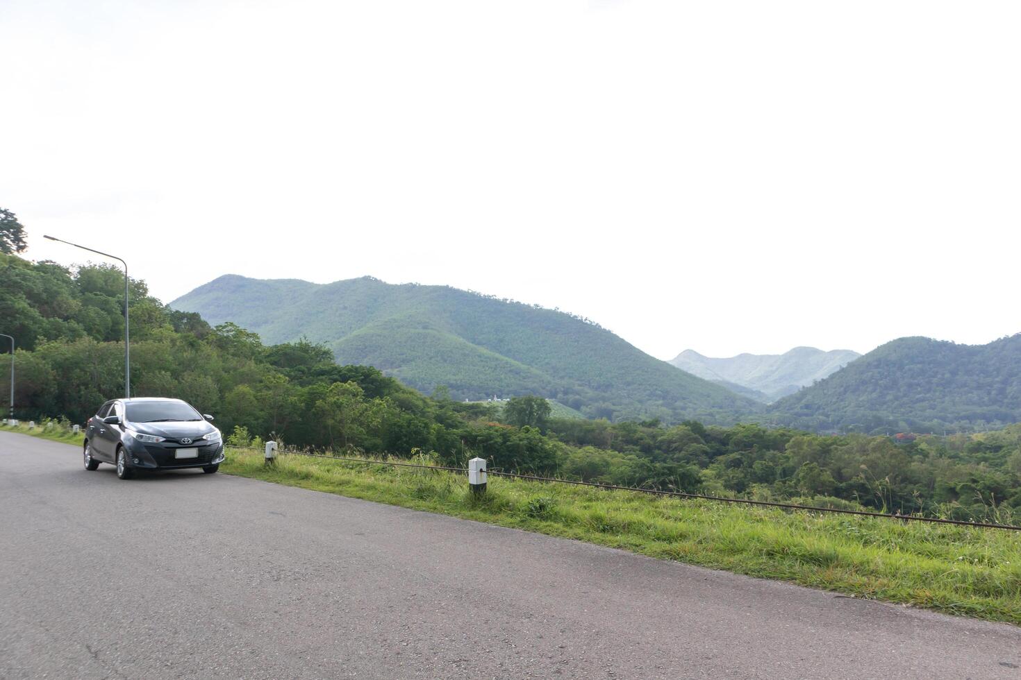 el coche está aparcado en una carretera alta. con montañas y cielo de fondo foto