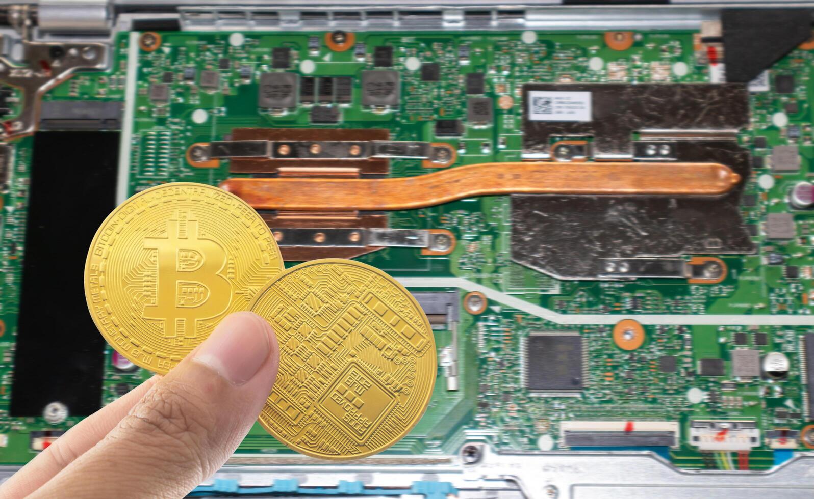Bitcoin holding in hand with motherboard blurred background. photo