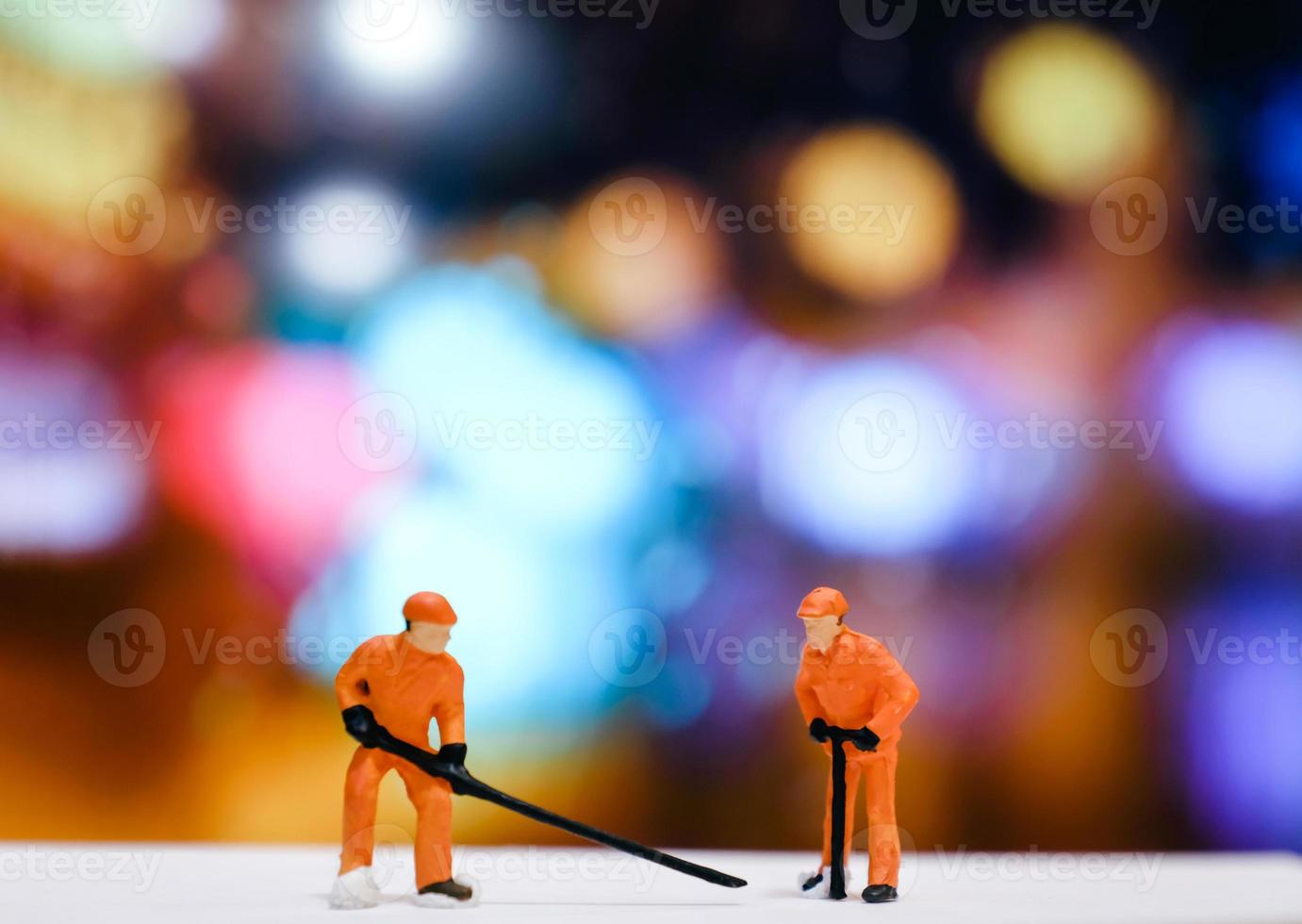 trabajadores en miniatura reparan la calle por la noche con fondo de luz bokeh, ingeniero y concepto mecánico foto