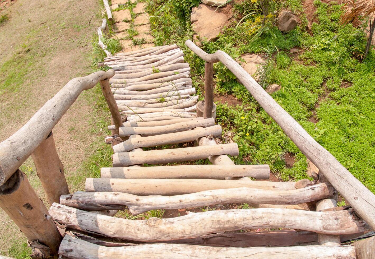 Staircase made of wood that is outdoors, Showing a path down to the ground with green grass. photo