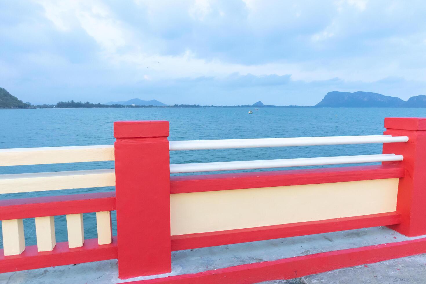 Concrete poles on the footbridge at sea With the background is a city and mountain photo