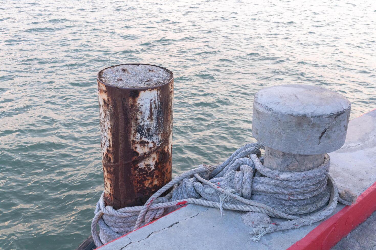Steel pillar in the sea Is tied with a concrete post with a rope photo