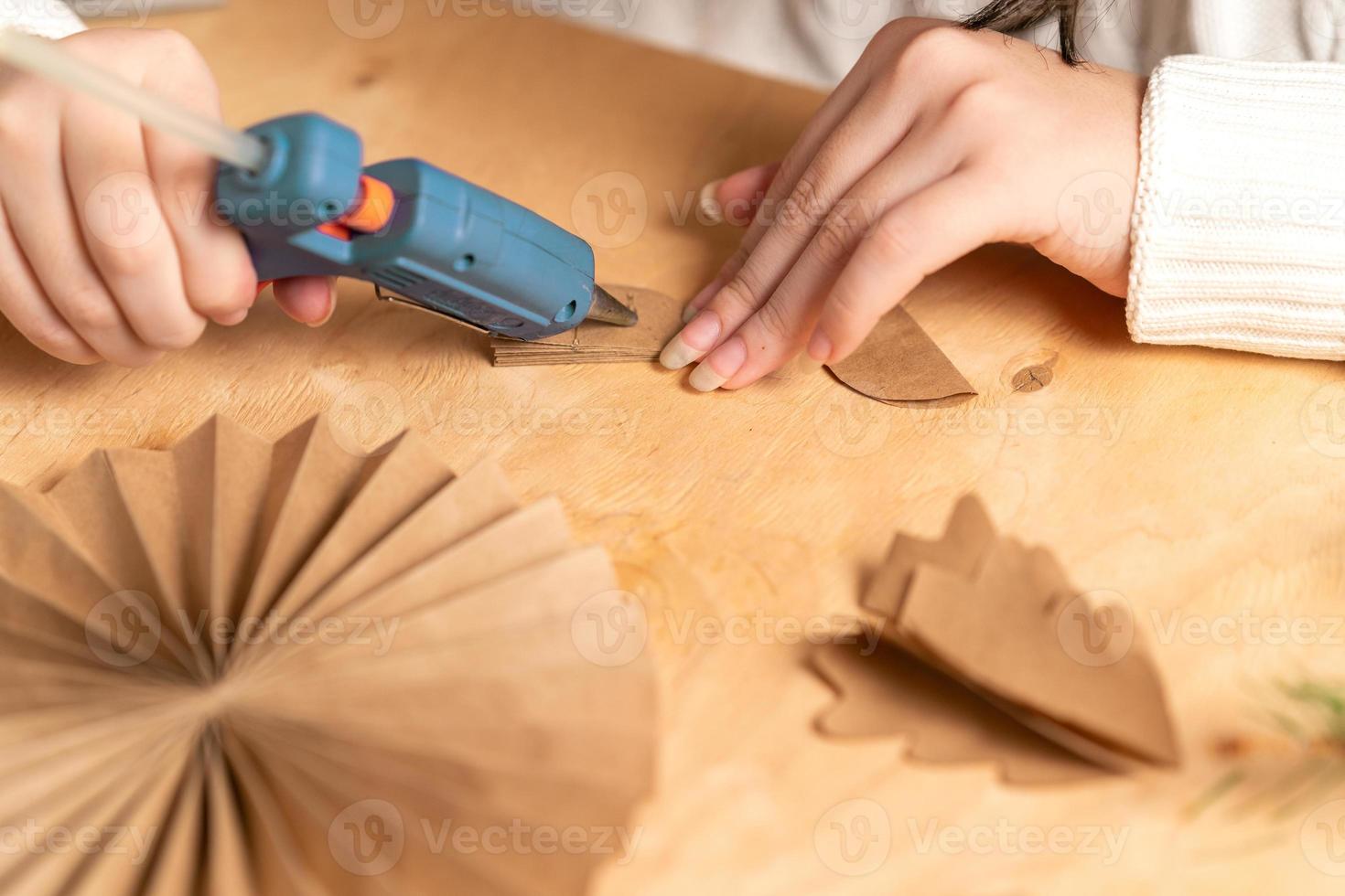 girl makes Christmas tree decorations out of paper with her own hands. step 3. step-by-step instruction photo