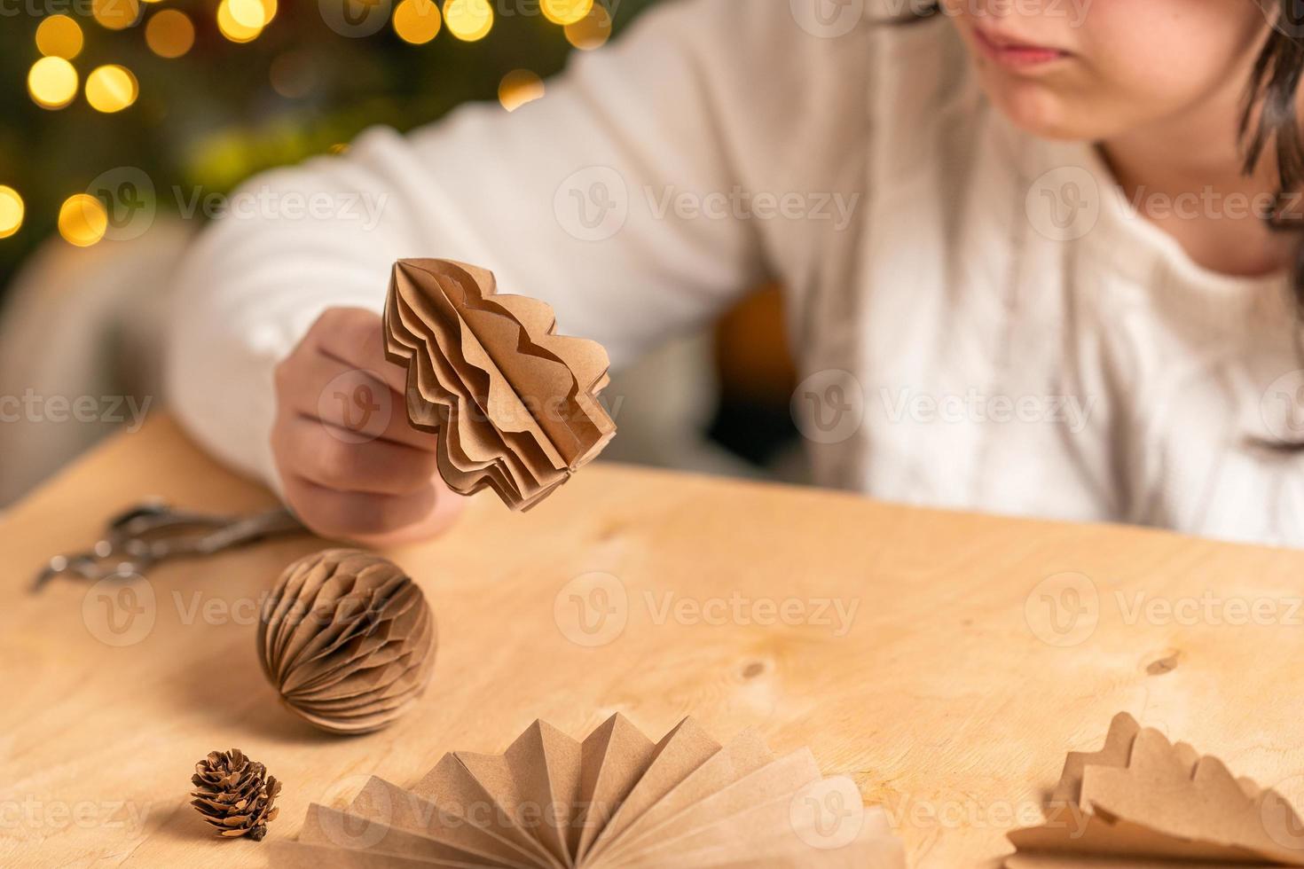 la niña hace decoraciones para árboles de navidad con papel con sus propias manos. paso 5. instrucción paso a paso foto