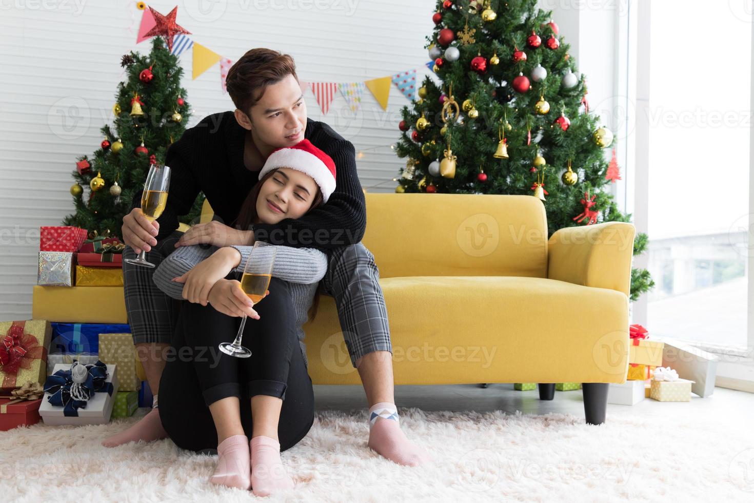 Beautiful young couple is holding glasses of champagne, smiling and affectionate while celebrating New Year at home photo