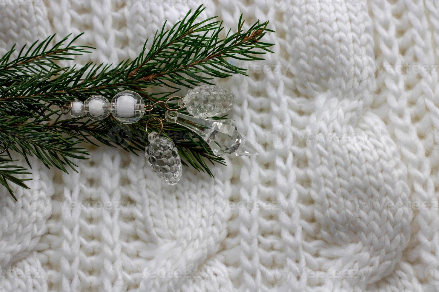 Background for Christmas and new year cards with a branch of spruce and red berries of rosehip on a white knitted cloth. Copy space photo