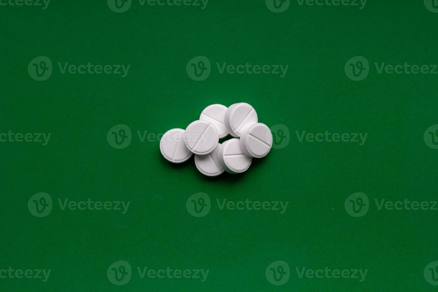 White squashed pills on green background. Crushed tablets. Medicine background. photo