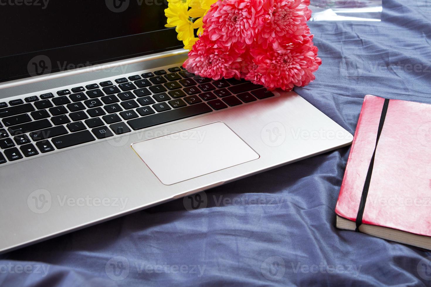 Hands, computer keyboard, bed top view. Workplace background, work at home, notepad and flowers photo