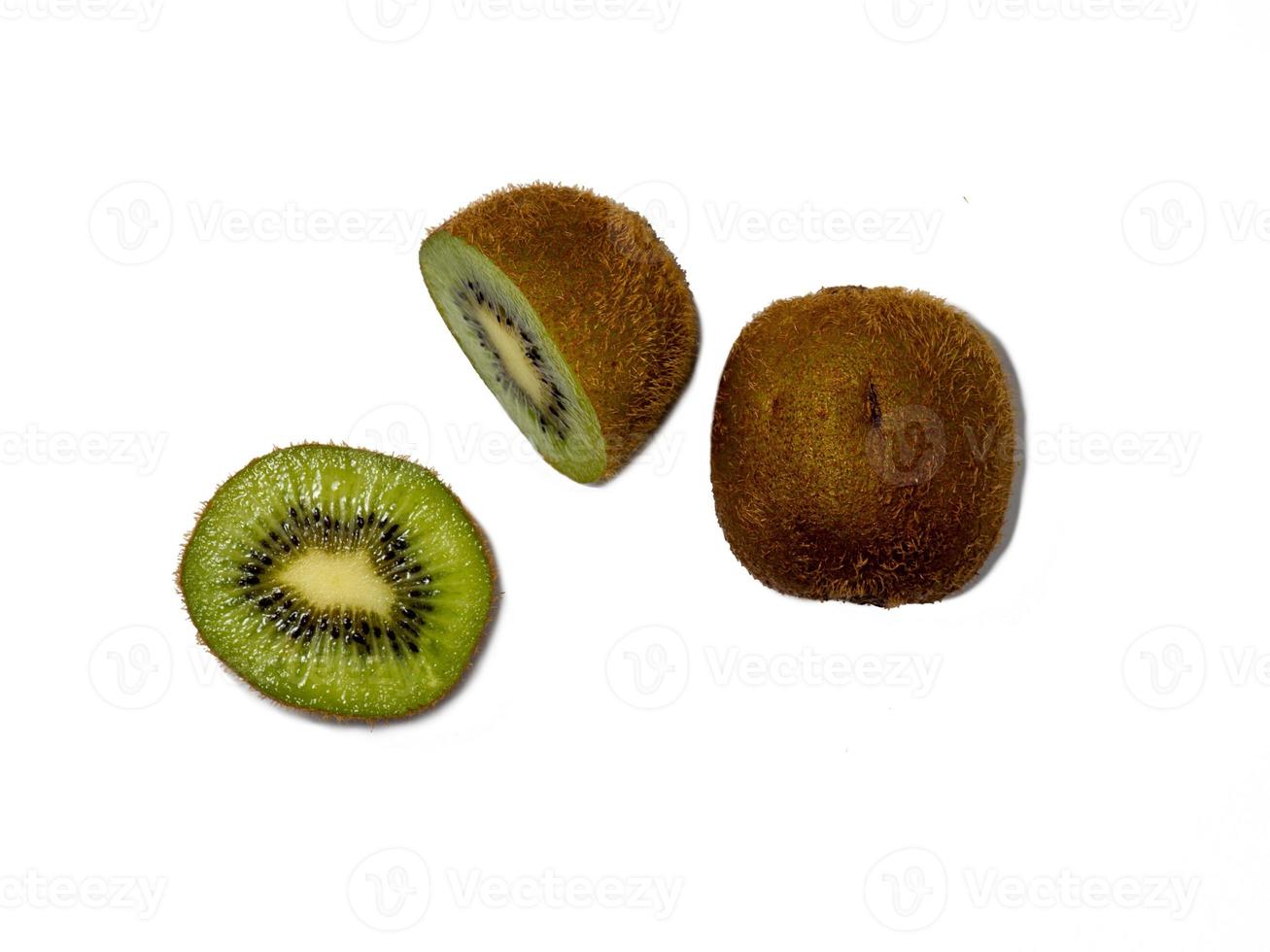 un kiwi sin pelar entero y otro cortado. foto