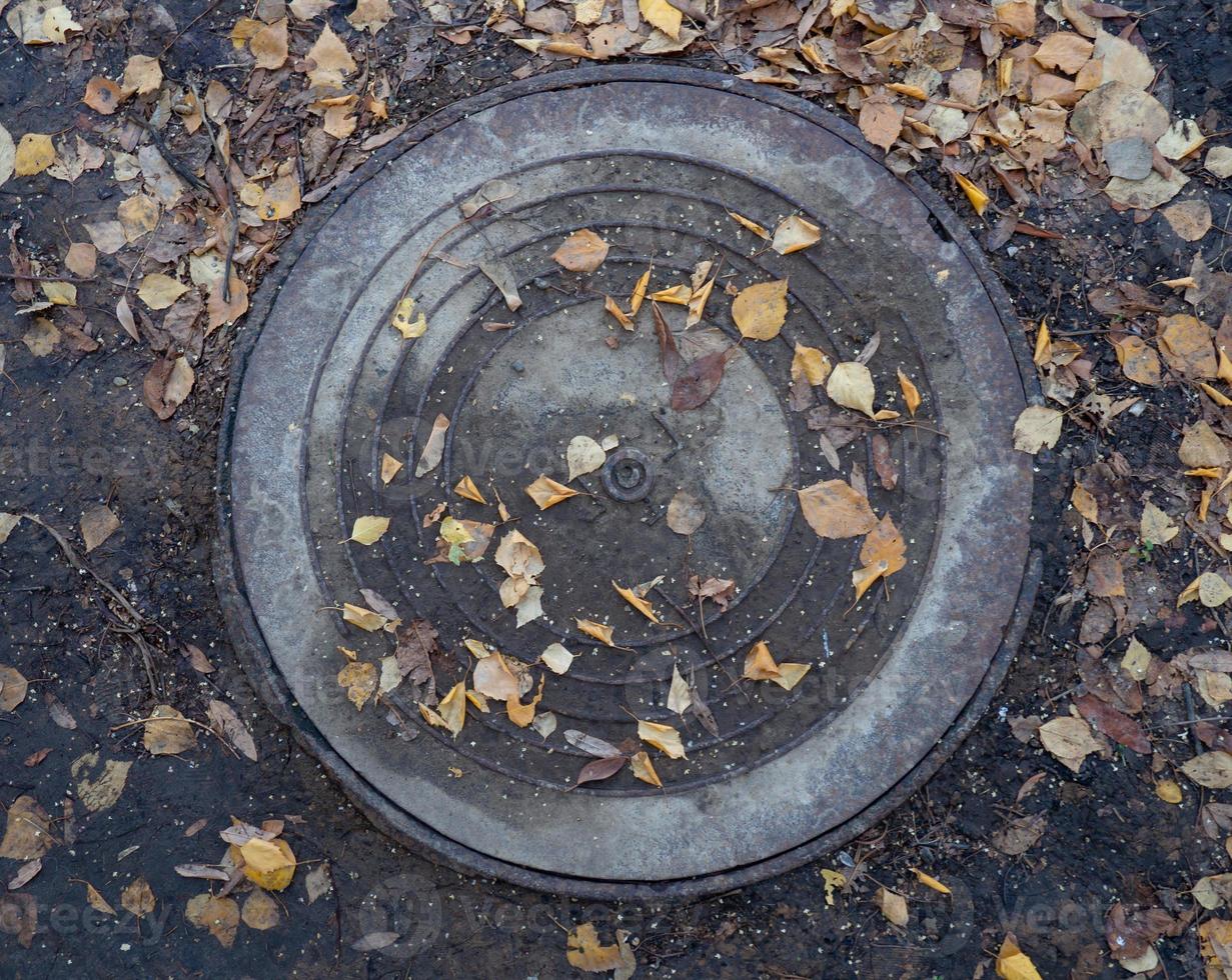 Manhole in autumn foliage. Slush, bad weather photo