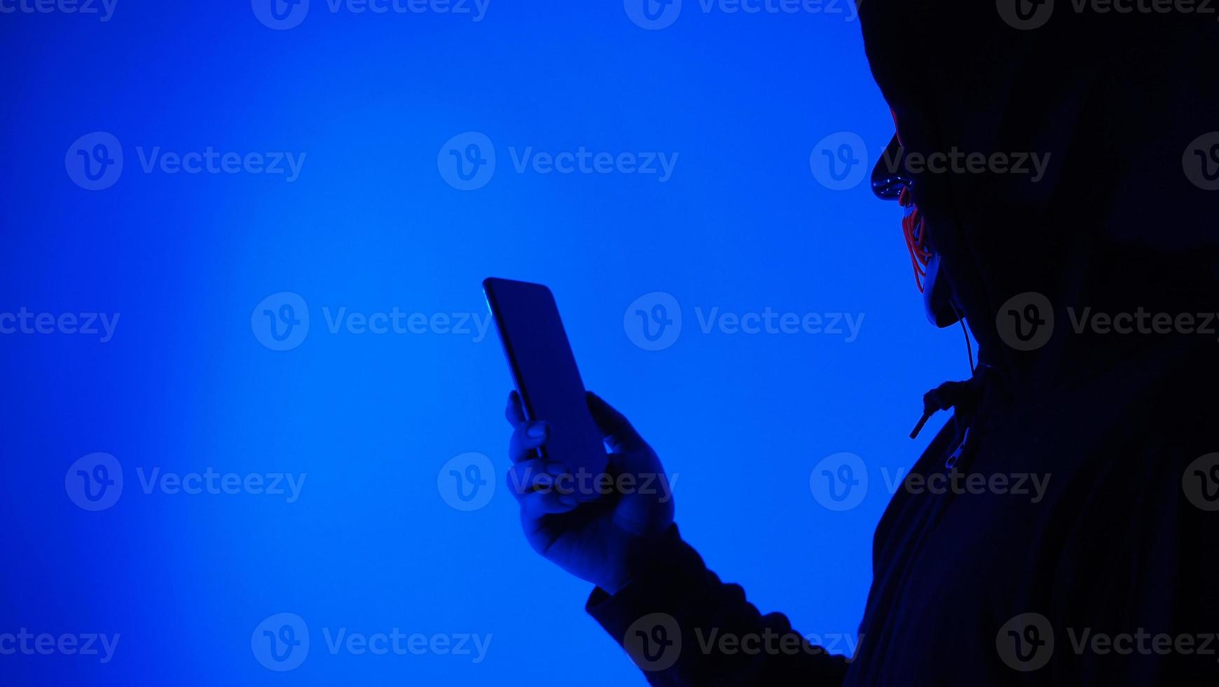Digital security Concept. Anonymous hacker with mask holding smartphone hacked. photo