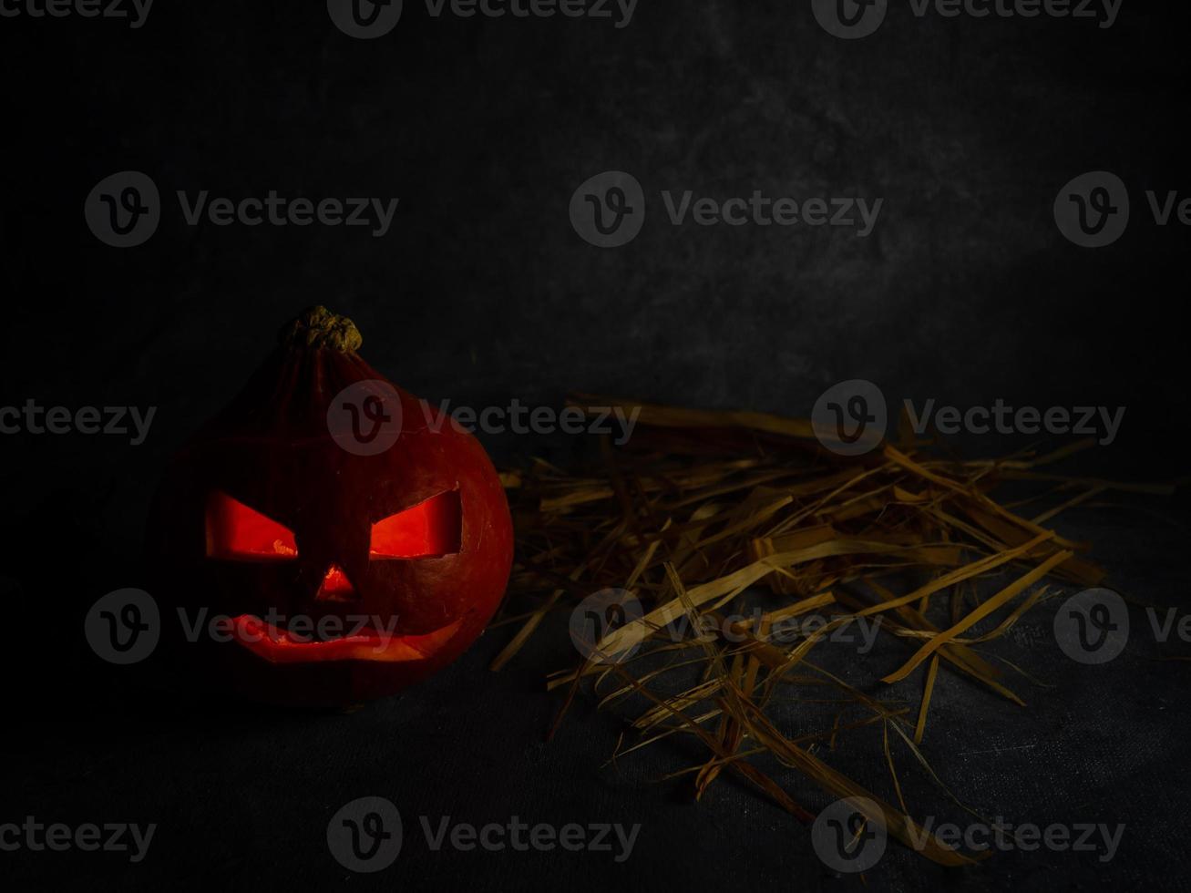 Still life for halloween. Pumpkin and straw on a black background. photo