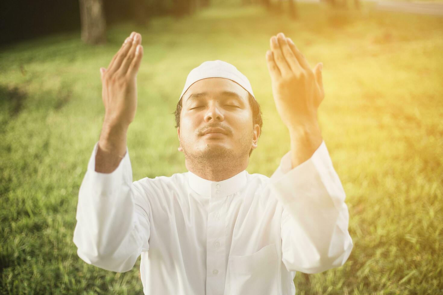 Asian Muslim man praying To Allah God Of Islam on green. photo