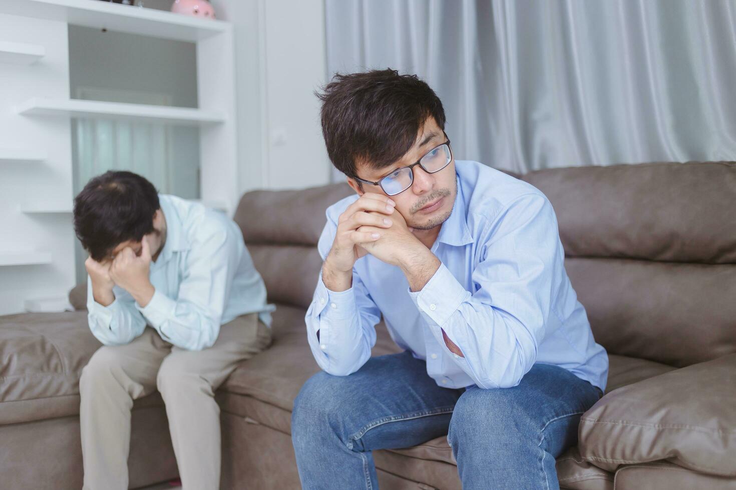 Asian gay couples are quarreling, angry or sad on sofa in home, LGBTQ concept. photo