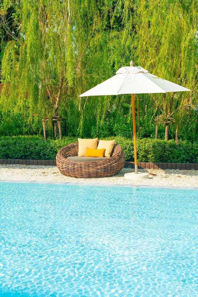 outdoor patio chair with pillow and umbrella around swimming pool photo