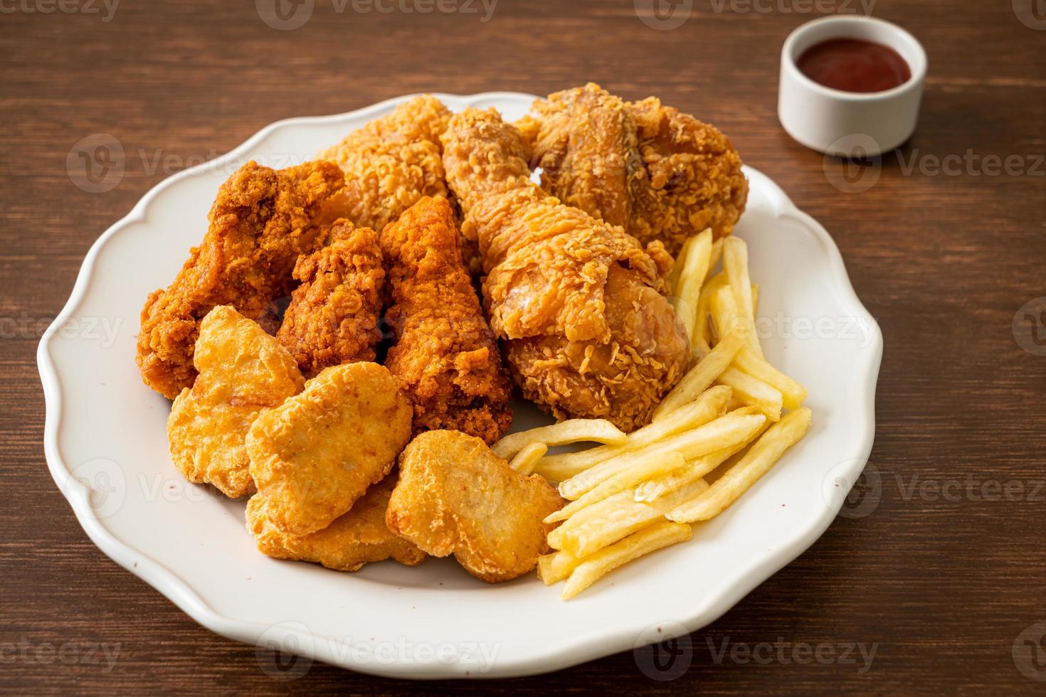 pollo frito con papas fritas y nuggets en un plato foto