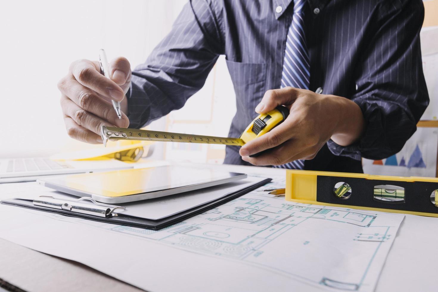 business hand working and laptop with on on architectural project at construction site at office desk in office photo