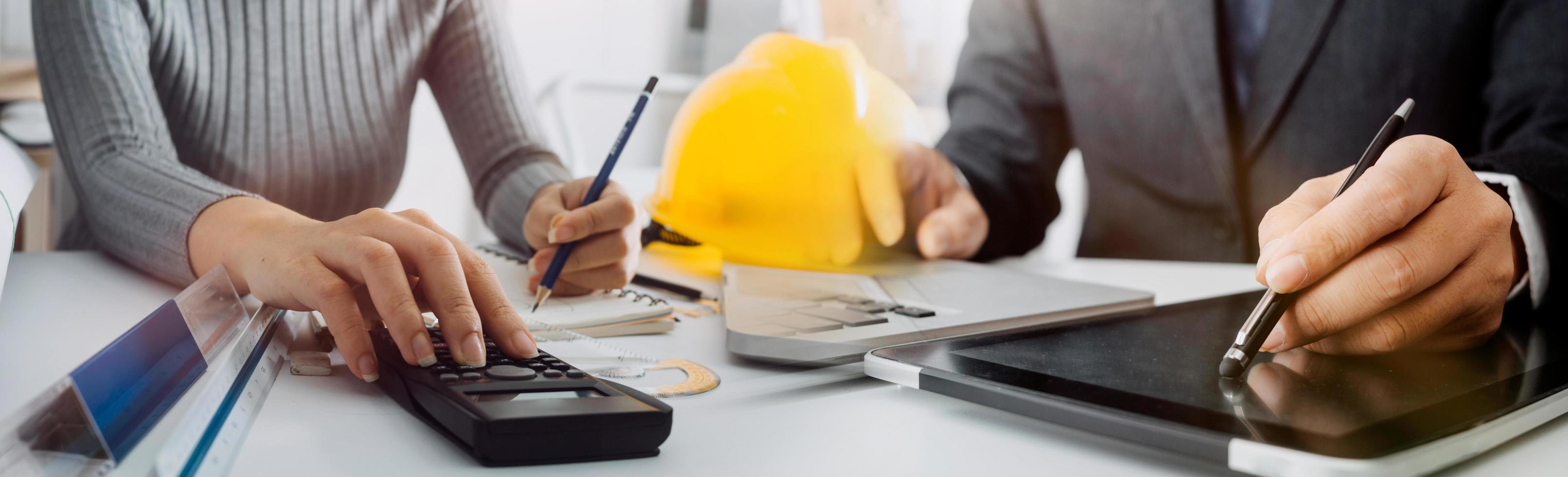 business hand working and laptop with on on architectural project at construction site at office desk in office photo