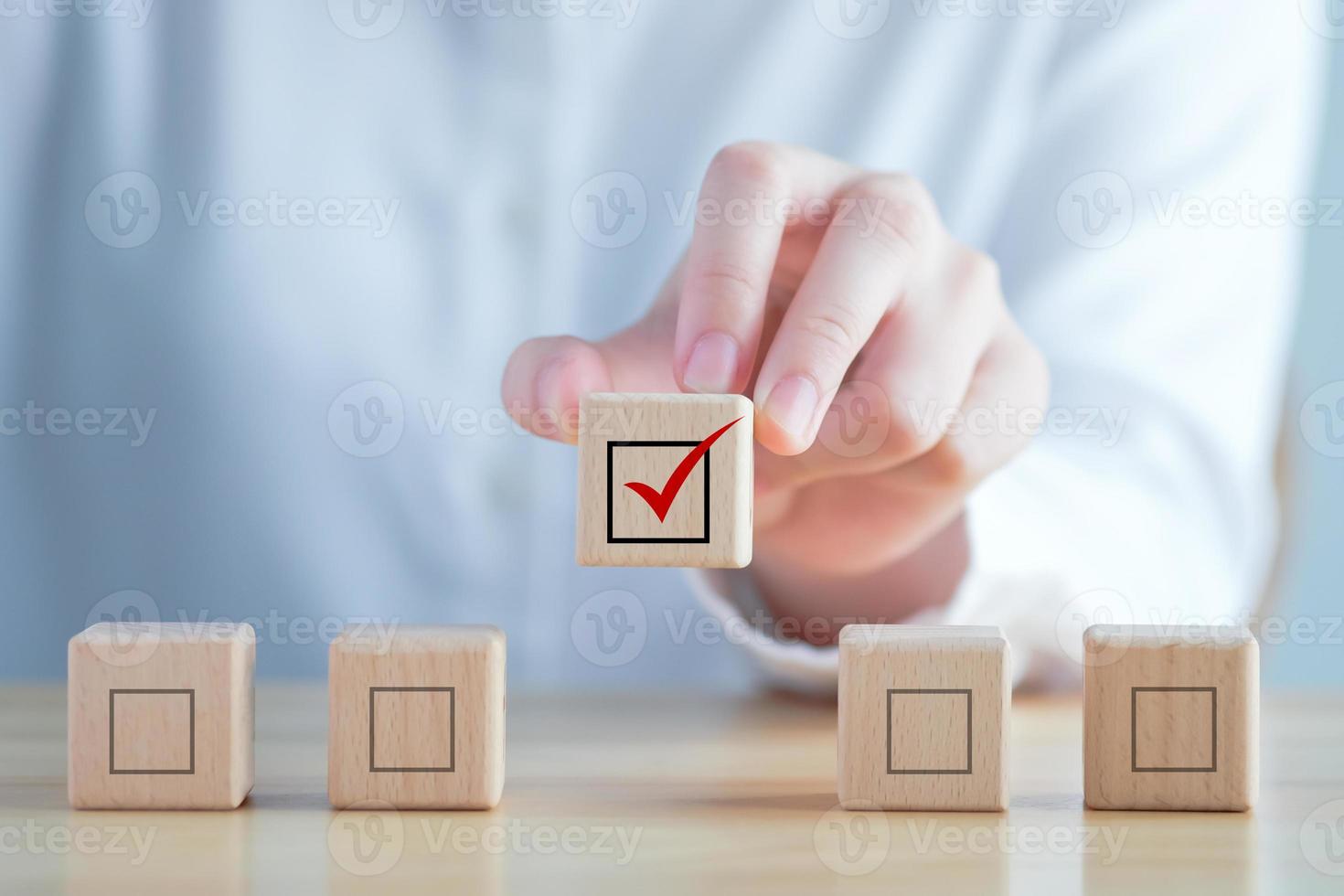 Elections and Voting, Vote, to do list, checklist, Task list, Survey and assessment concept. Hand holding check mark on wooden block and blank check box on wooden cubes photo