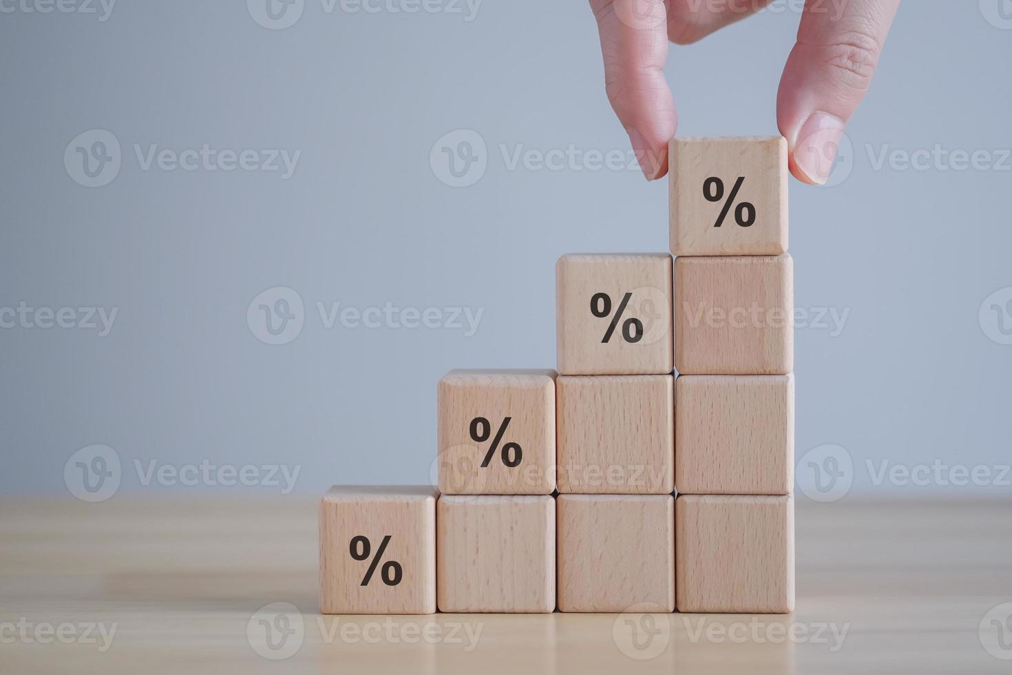 Interest rate finance and mortgage rates. Hand holding percentage sign on ladder of wooden blocks, financial growth, interest rate increase, inflation, sale price and tax rise concept. photo
