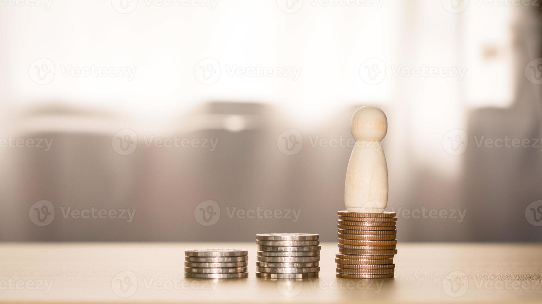 Business and financial success concept. A wooden figure stands on a coin stack. Saving and investment for the future, loans, banking, stock, and fund. photo