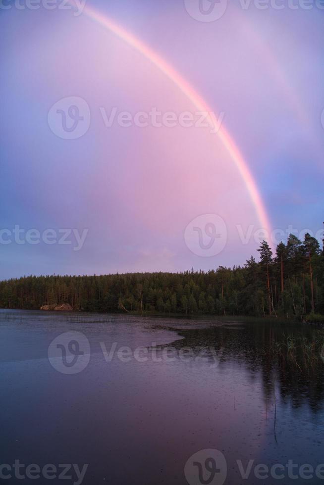 arco iris reflejado en el lago cuando llueve. en el lago cañas y nenúfares. foto