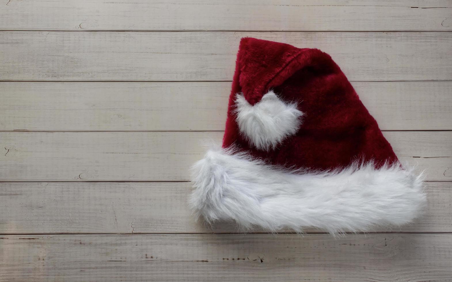 Red Santa Claus hat isolated on wooden background. Christmas decoration. Christmas ornaments. Flat lay. photo