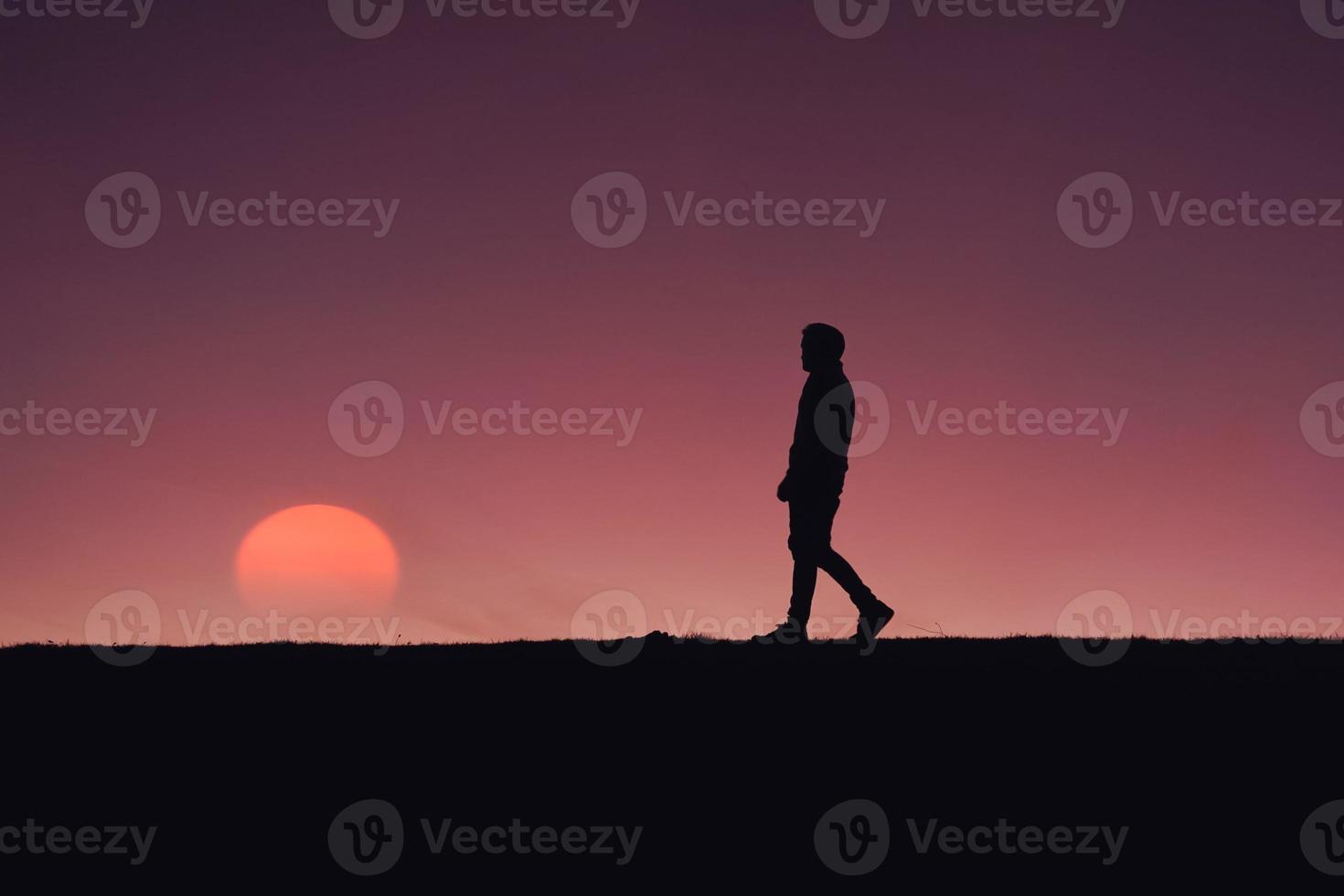 man trekking in the countryside with a beautiful sunset background photo