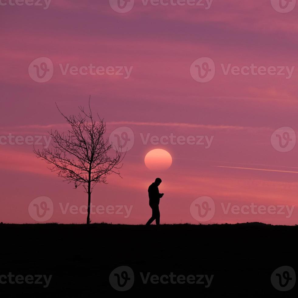 hombre caminando por el campo con un hermoso fondo de puesta de sol foto