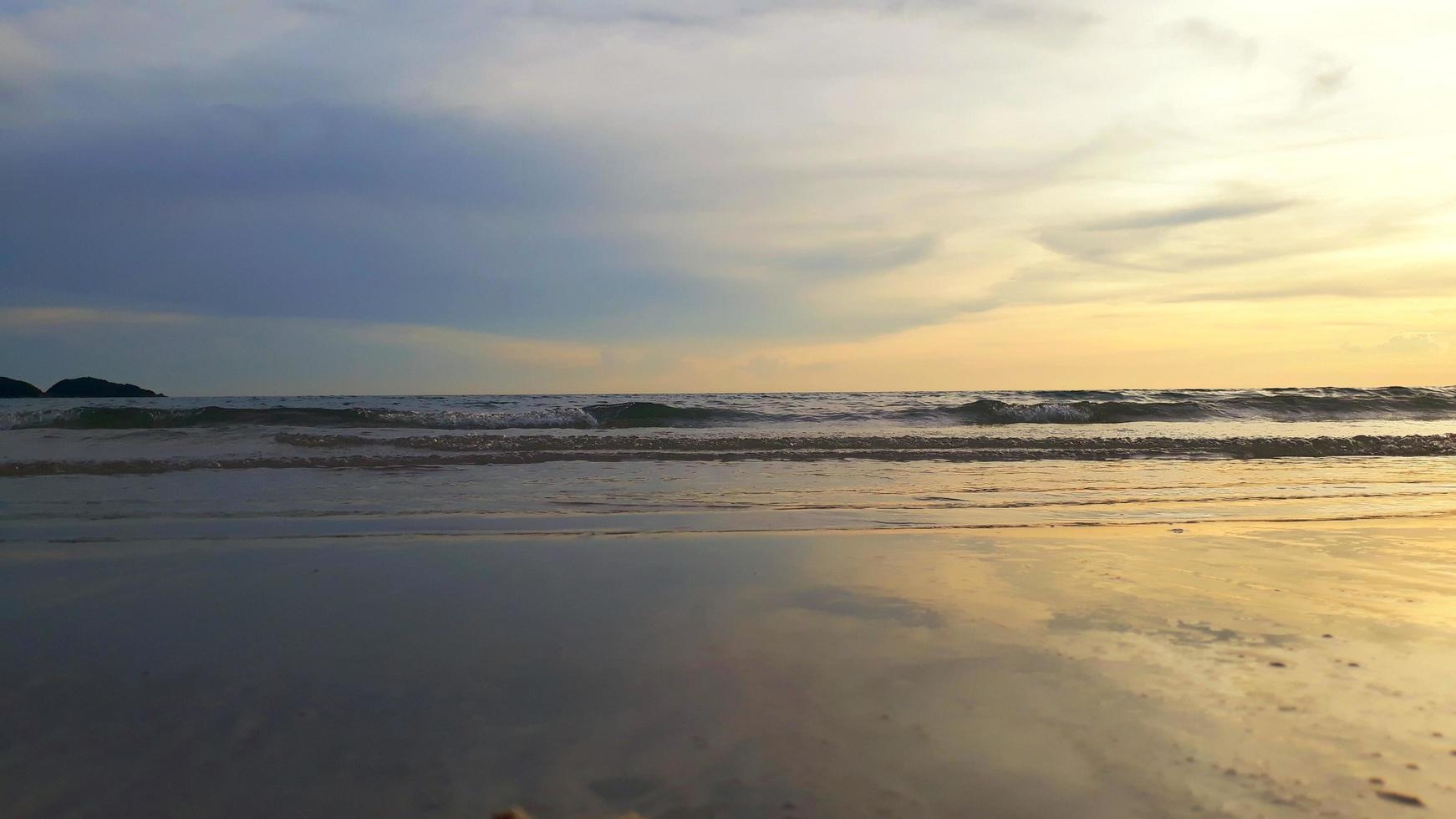 Wide angle view of the sea.  Ocean waves and blue sky mixed with yellow as the sun goes down. photo
