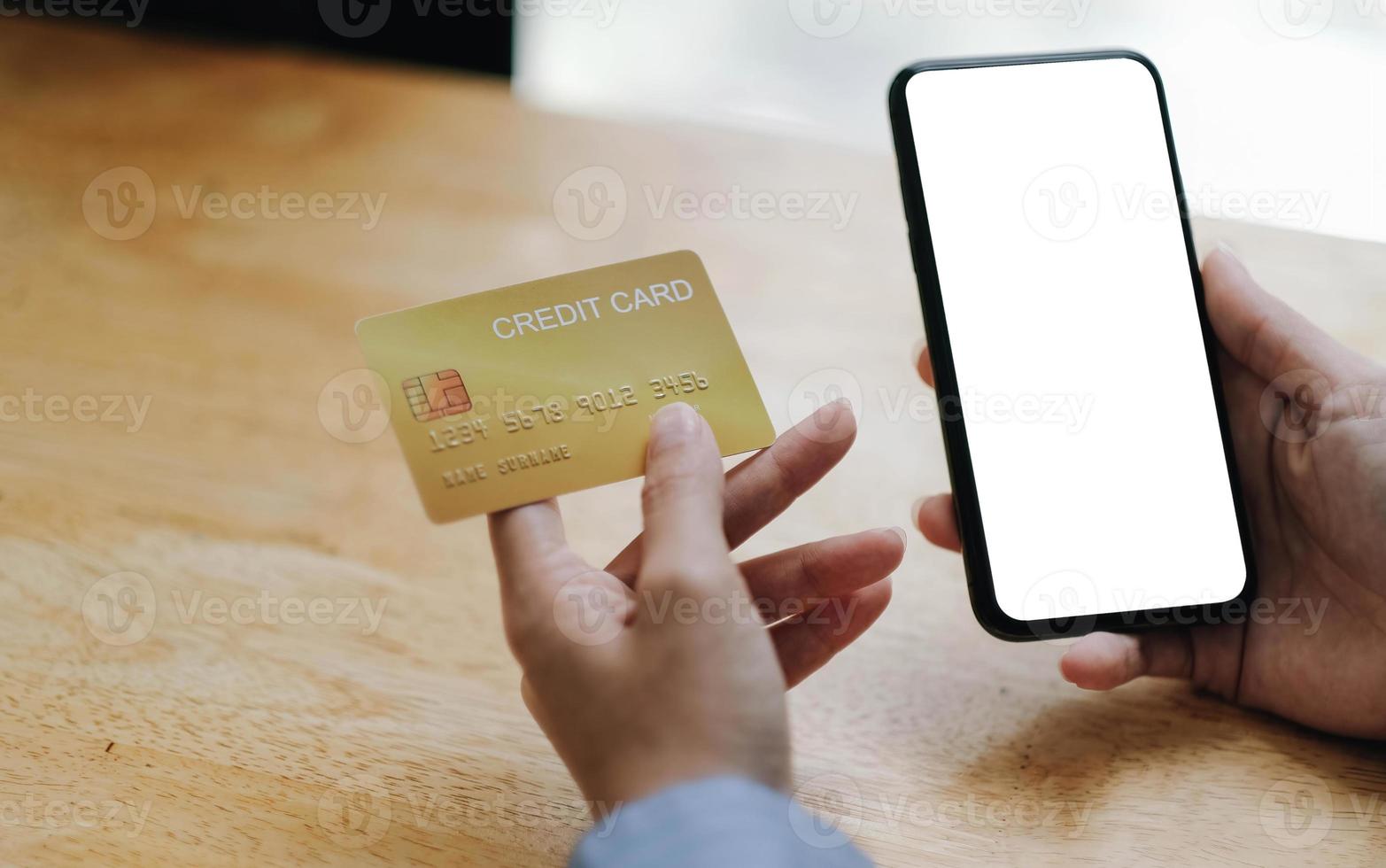 mujer de cerca sosteniendo un teléfono móvil con una pantalla blanca y tarjeta de crédito. concepto de compras en línea foto