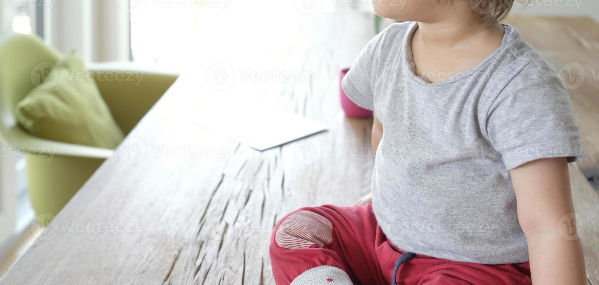 Anonymized view of a baby sitting on a table photo