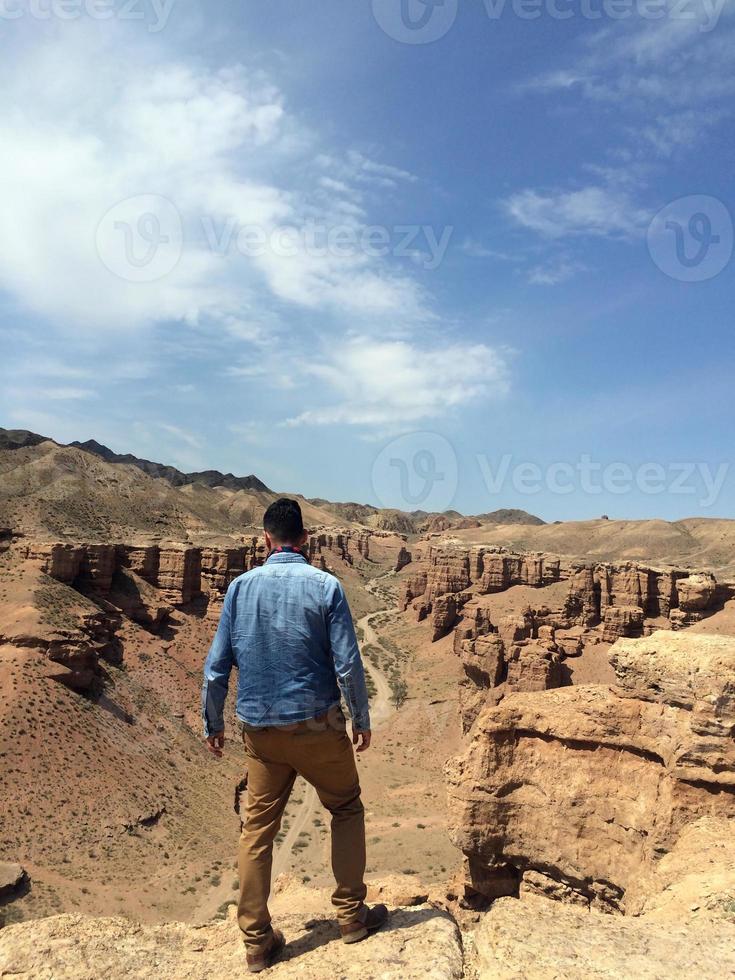 hombre en camisa de mezclilla con vistas al cañón charyn en kazajstán foto