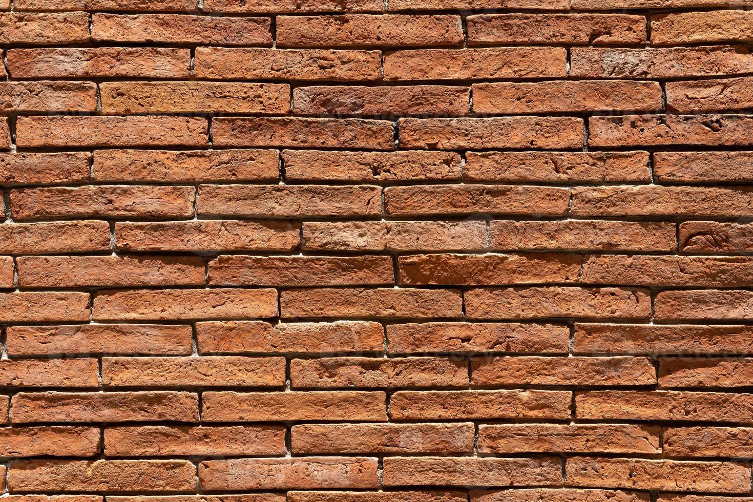Red brick wall background. A wall of old, cracked bricks, with a weathered and faded surface. Restored brickwork of an old house. photo