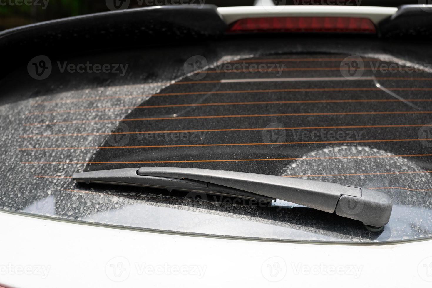 rear window hatchback dirty car rear view on a dusty glass. Dirty and dusty rear window of a white or gray car. Do not forget to wash your cars manually or at car washes photo
